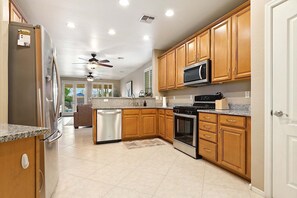 A modern kitchen with wooden cabinets, stainless steel appliances, and a central island. - Goodyear Springs * Private Pool & Community Playground (Goodyear)