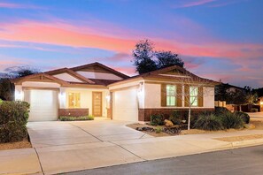 Une maison à deux étages avec un garage, un porche à l’avant et une pelouse bien entretenue.