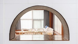 Un comedor con una mesa, sillas y un espejo arqueado grande que refleja la habitación.