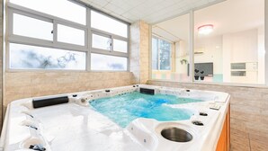 Un jacuzzi con vistas a un paisaje nevado a través de amplios ventanales.