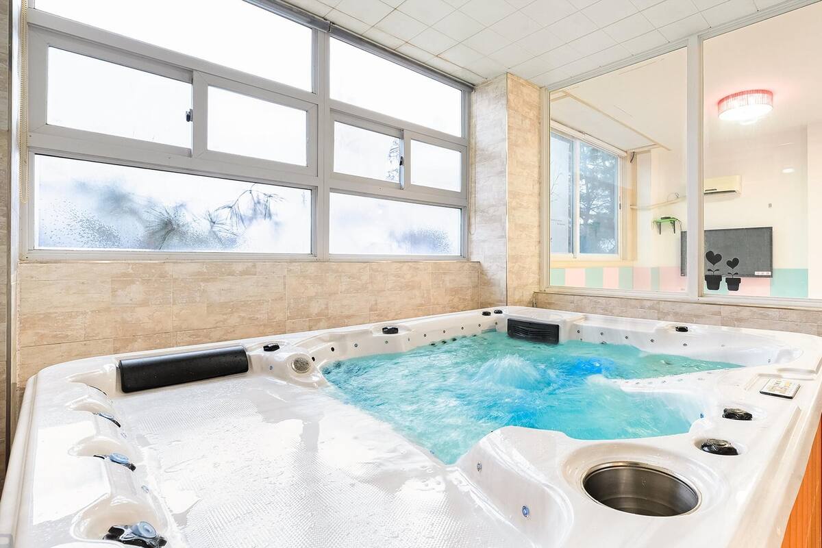 Un jacuzzi con vistas a un paisaje nevado a través de amplios ventanales.