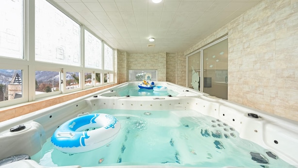 Un área de spa con dos jacuzzis, uno con un aro inflable azul.