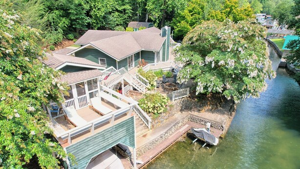 A house with a dock extending into a river, surrounded by lush greenery.