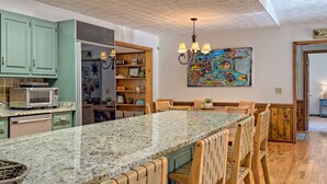 A kitchen with a granite countertop, wooden chairs, and a dining area with a table and chairs.