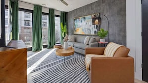 Una sala de estar moderna con un sofá, un sillón, una mesa de centro y un cuadro en la pared.