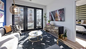 Una sala de estar moderna con un sofá, una mesa de centro y un ventanal con vistas a edificios.