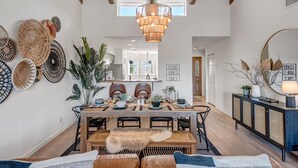 A dining area with a wooden table, chairs, and a chandelier. There are woven baskets on the wall and a mirror on the right. - Experience luxury at Sedona Tanglewood Treasure, a 2BR oasis in Village of Oak Creek. (Sedona)
