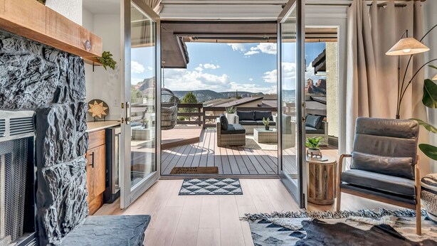 A modern living room with a fireplace, a sofa, and a view of a deck with outdoor furniture. - Experience luxury at Sedona Tanglewood Treasure, a 2BR oasis in Village of Oak Creek. (Sedona)