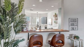 A modern kitchen with a central island, two brown leather chairs, and a 'Good Vibes Only' sign on the wall. - Experience luxury at Sedona Tanglewood Treasure, a 2BR oasis in Village of Oak Creek. (Sedona)