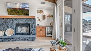 A living room with a stone fireplace, a large window, and a view of the outdoors. - Experience luxury at Sedona Tanglewood Treasure, a 2BR oasis in Village of Oak Creek. (Sedona)