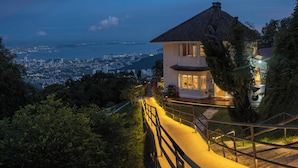 A house with a balcony overlooking a cityscape at dusk. - Eythrope Boutique Villa (George Town)