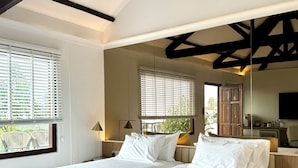 A double bed with white linens, two bedside lamps, and a wooden nightstand. - Eythrope Boutique Villa (George Town)