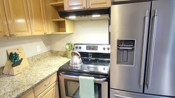 A kitchen with wooden cabinets, a stainless steel refrigerator, a stove, and a water dispenser.