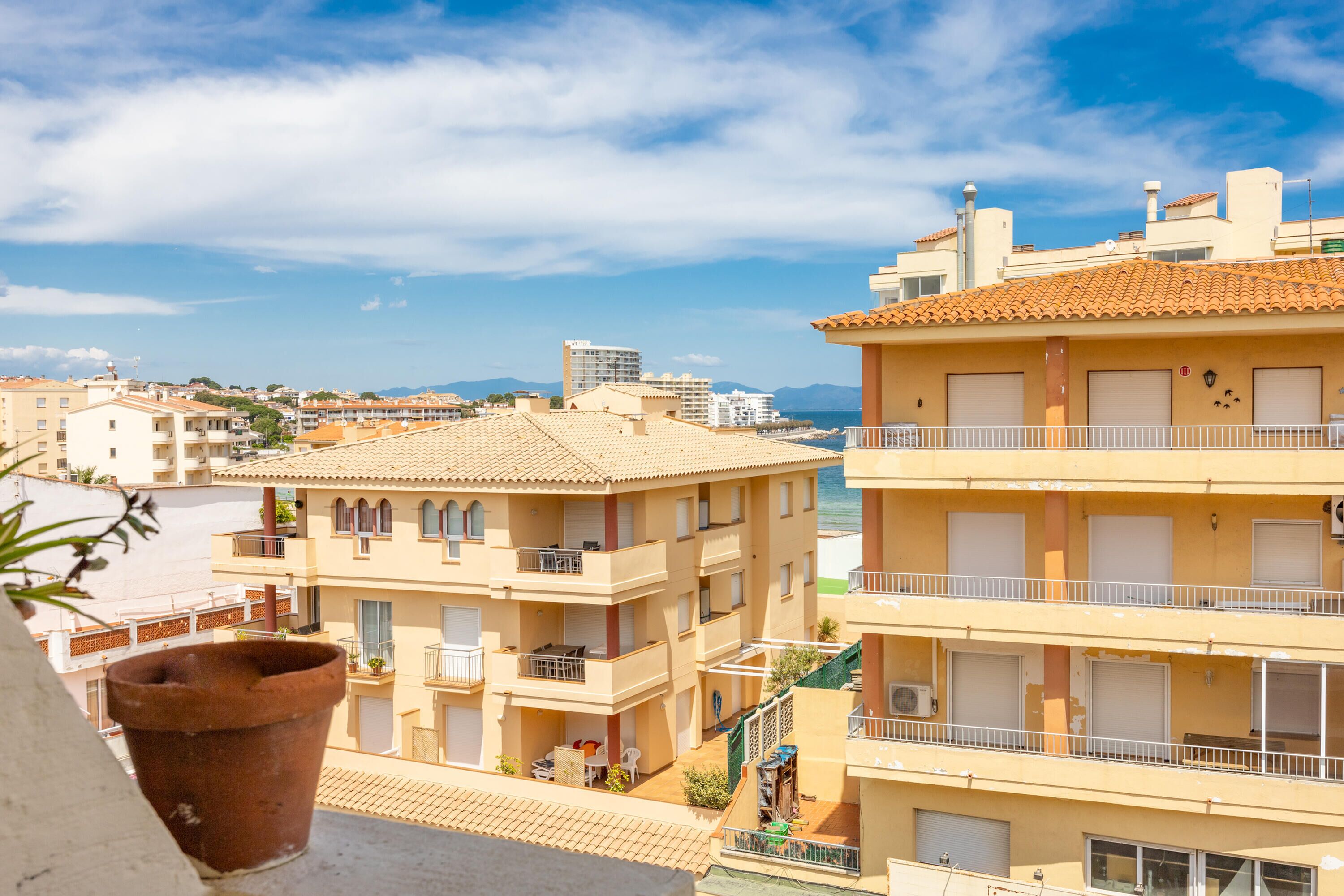 A multi-story building with balconies, a terrace, and a view of the sea.