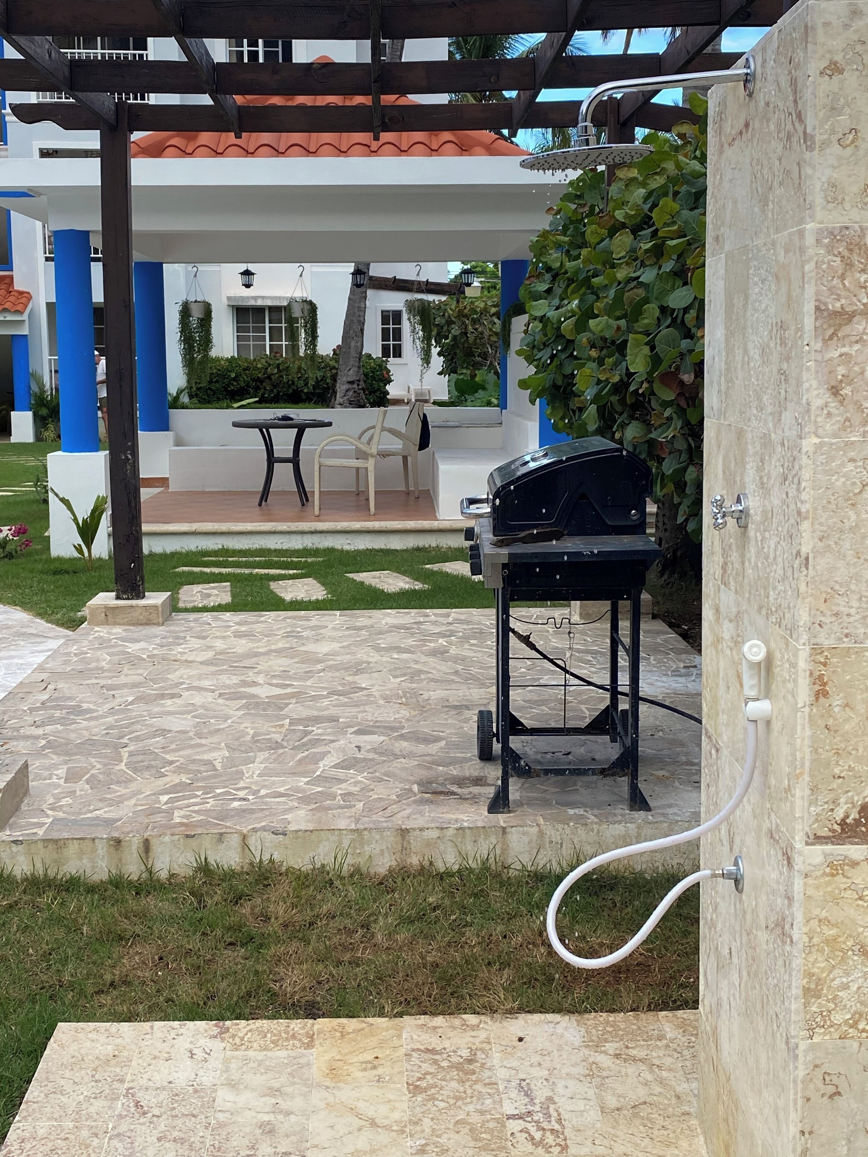 Eine Außenpatio mit Grill, einer Pergola und einem gefliesten Boden.