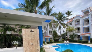 Ein Resort mit Swimmingpool, Palmen und einem überdachten Bereich mit Dusche.