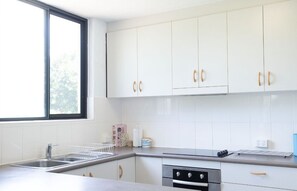 Eine moderne Küche mit weißen Schränken, Edelstahlgeräten und einem Fenster für natürliches Licht.
