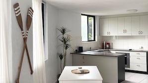 Eine moderne Küche mit weißen Schränken, einer zentralen Kochinsel und einem Fenster mit Vorhängen.