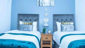 Ein Schlafzimmer mit zwei Betten, einem Nachttisch, Wandbild und dekorativen Kissen.