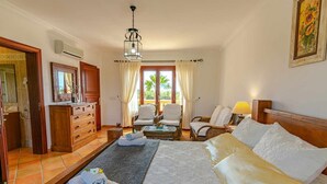 A hotel room with a bed, two chairs, a small table, a dresser, and a window with curtains. - Villa Sanchez (Campos)