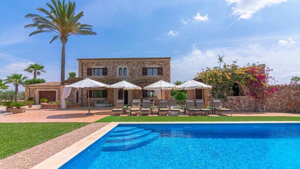 A large stone building with a swimming pool, outdoor seating, and palm trees. - Villa Sanchez (Campos)