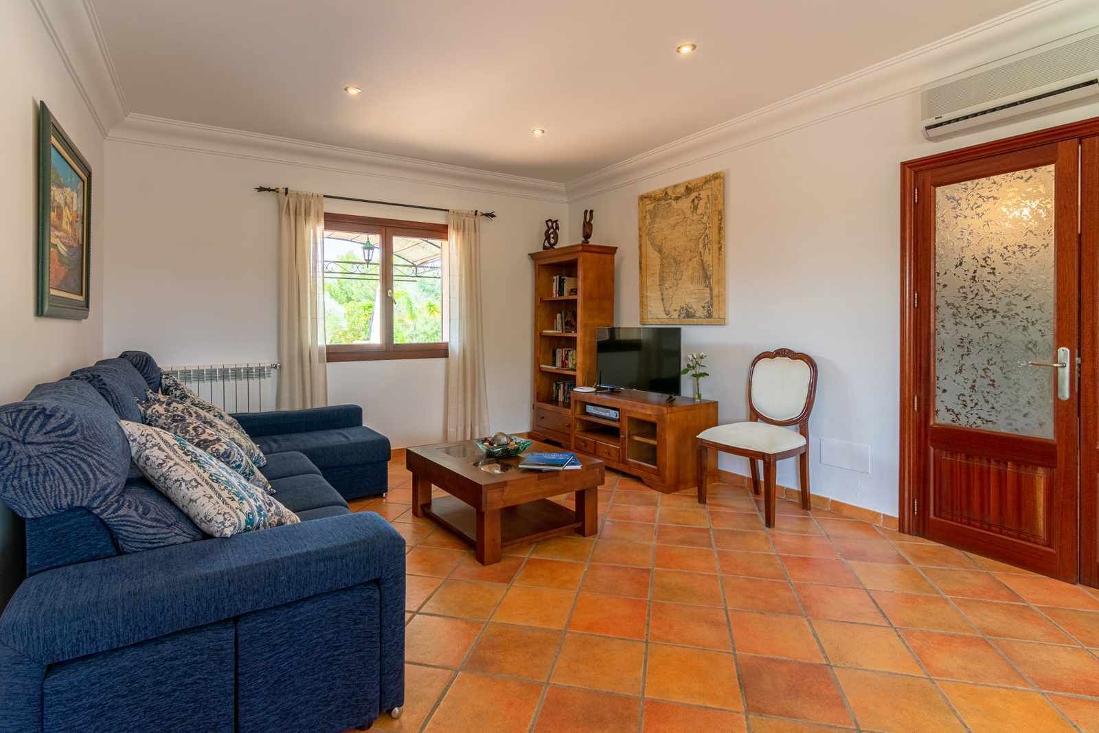 A living room with a sofa, coffee table, TV stand, and a wooden chair.