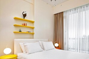 A modern hotel room with a bed, yellow nightstands, and a window with sheer curtains. - G Tower Furnished Apartment Rentals (Istanbul)