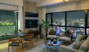 A modern living room with a city view, a dining area, and a large window. - G Tower Furnished Apartment Rentals (Istanbul)