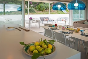 A modern kitchen with a large island, dining area, and outdoor patio.
