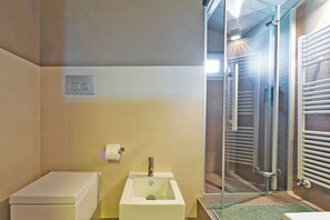 A bathroom with a toilet, sink, and glass shower enclosure.