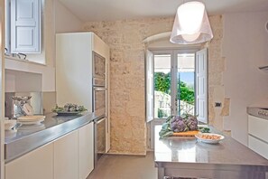 Una cucina con parete in pietra, una finestra vista panoramica e un lampadario moderno.