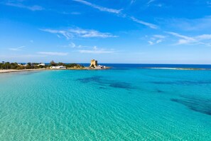 A coastal view with clear turquoise waters, a distant castle-like structure, and a clear sky. - Casa Lory 3 Cozy and near the Sea, Nardò, Italy (Nardò)