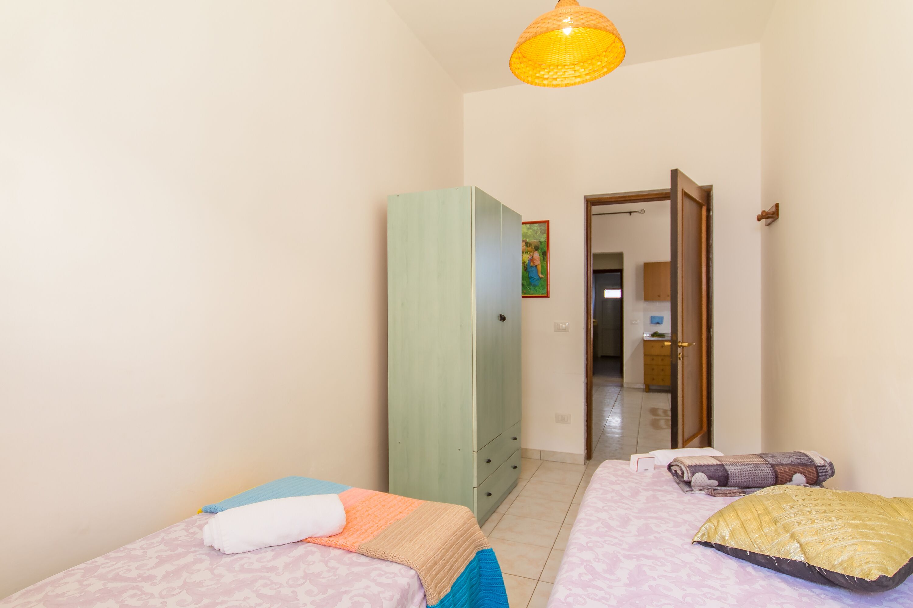 Ein Zimmer mit zwei Betten, einem Kleiderschrank und einer Tür zu einem weiteren Raum.