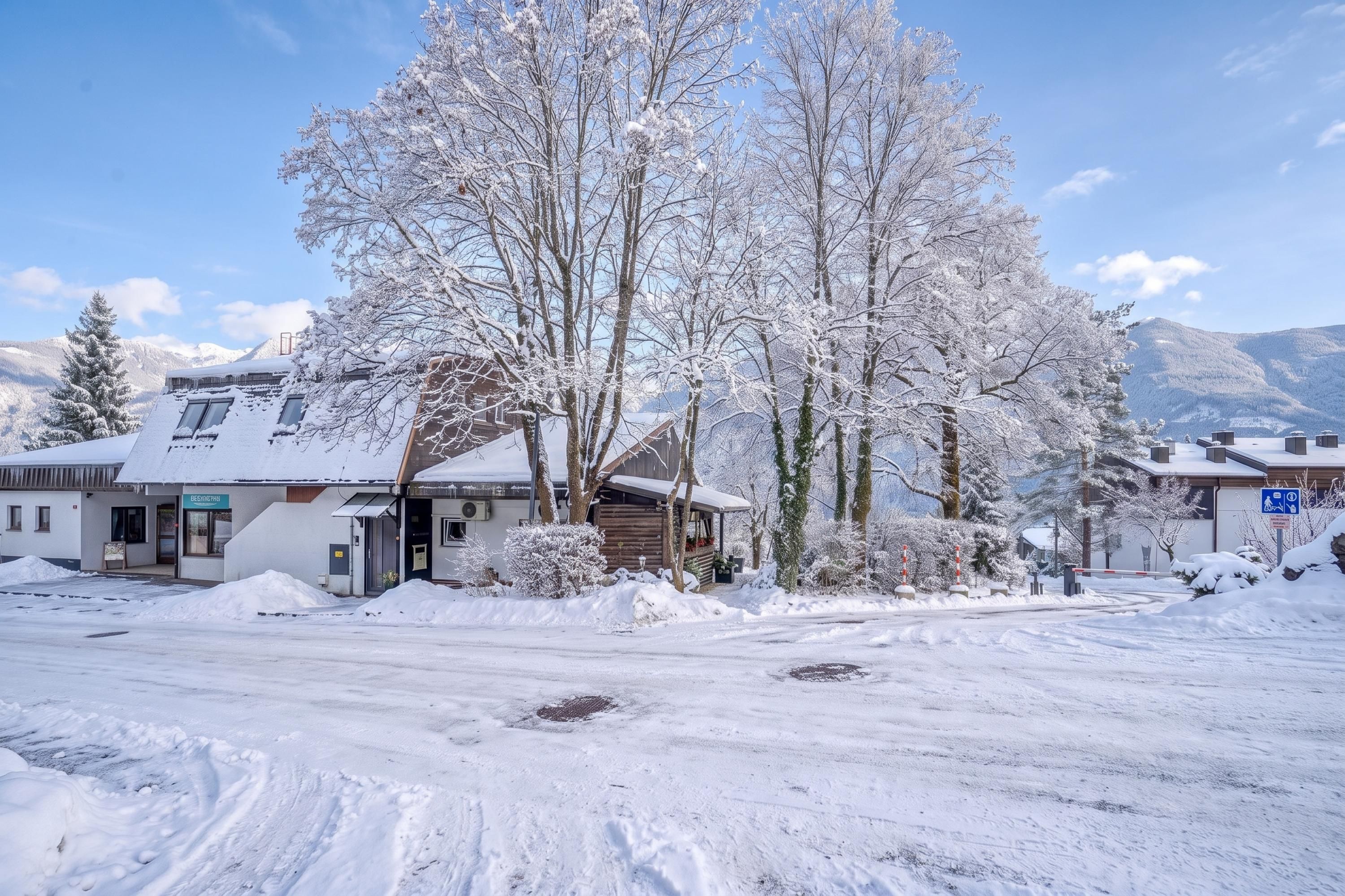 A snow-covered landscape with buildings, a clear sky, and mountains in the background.