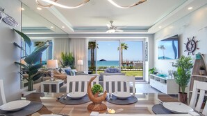 Ein modernes Wohnzimmer mit Blick auf den Strand, ein Essbereich mit Kochinsel und eine gemütliche Sitzecke.