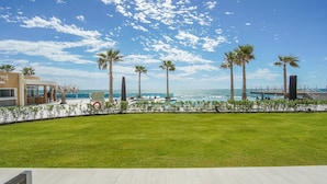 A resort with a pool, palm trees, and a view of the ocean.