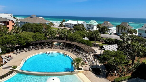 Un resort con una grande piscina, vista sulla spiaggia e diversi edifici.