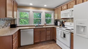 Une cuisine avec des meubles de rangement en bois, un lave-vaisselle blanc, une cuisinière et un four à micro-ondes.