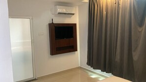 Une pièce dotée d’une porte coulissante, d’un téléviseur fixé au mur et d’un appareil de climatisation.
