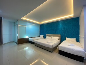A modern hotel room with a large bed, two smaller beds, a glass partition, and a blue textured wall. - Co-Didik Hotel (Kuantan)