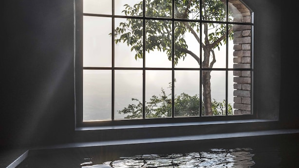 A room with a large arched window overlooking a tree and a body of water. - Monteverdi Tuscany (Sarteano)