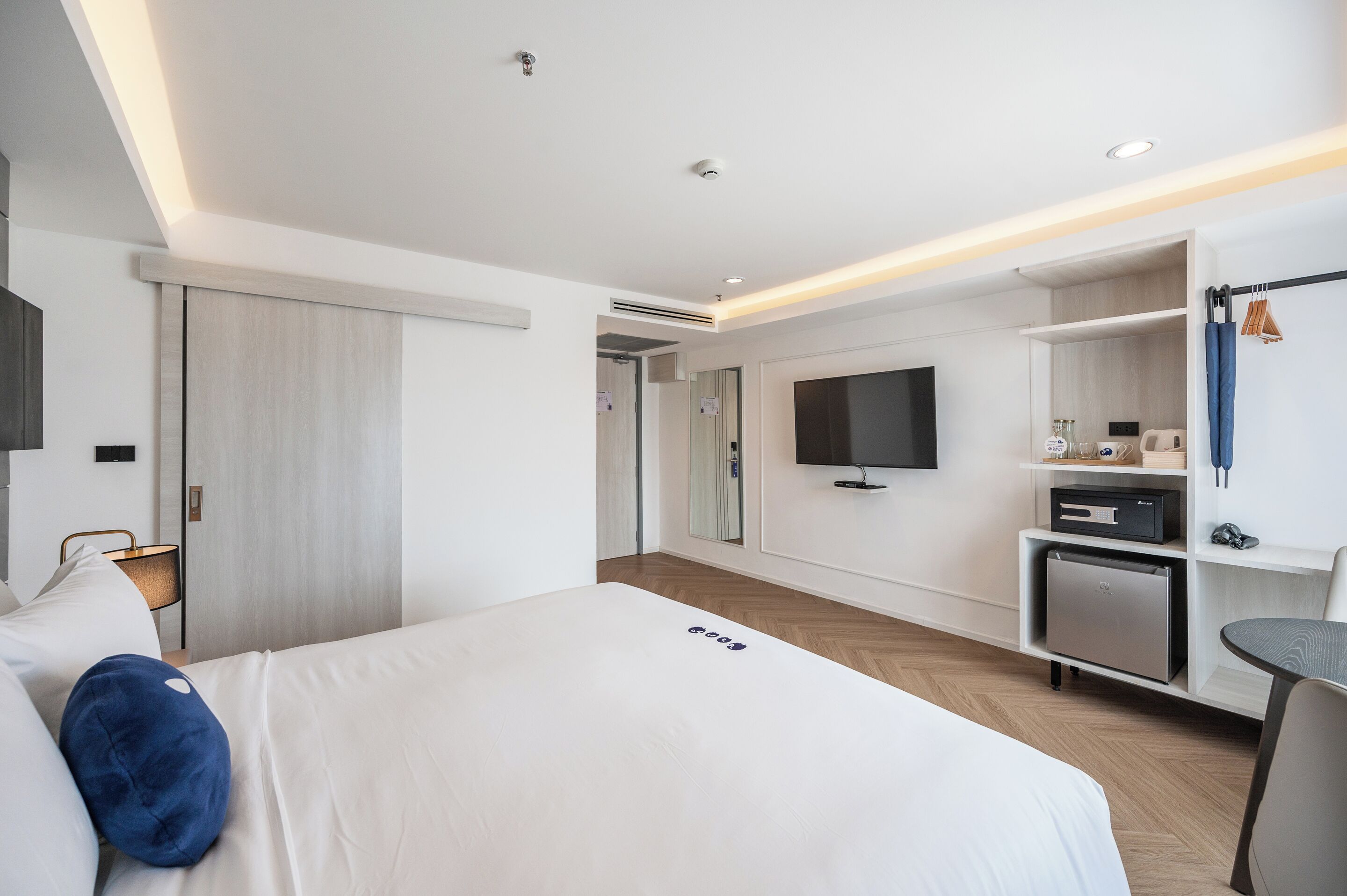 Een moderne hotelkamer met een groot bed, een televisie, een minibar en een bureau.