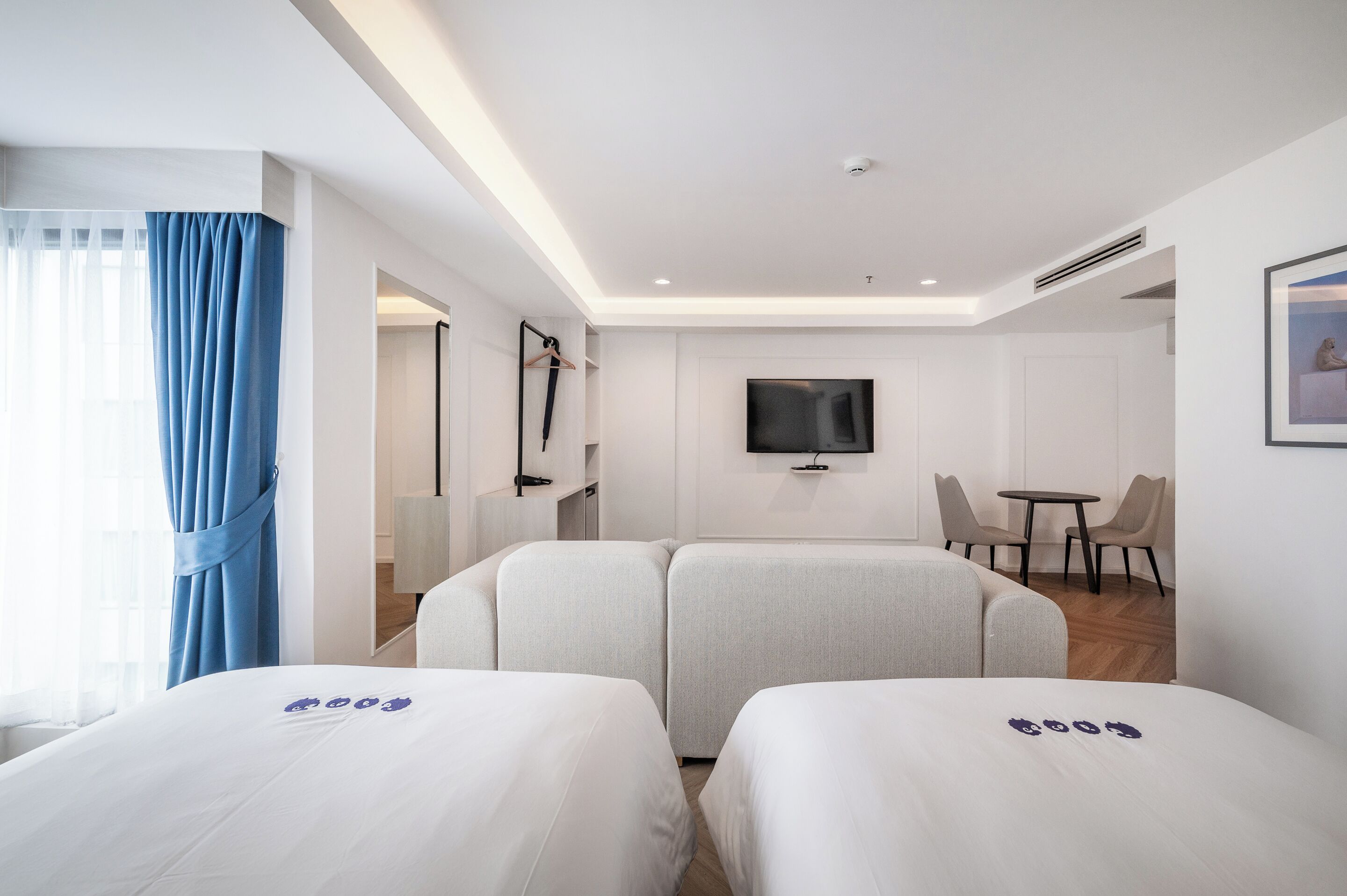 A hotel room with two beds, a TV, a small table, and a chair.