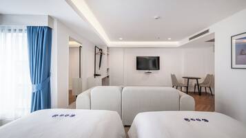 A hotel room with two beds, a TV, a small table, and a chair.