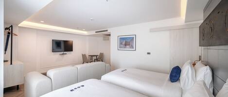Una habitación de hotel moderna con una cama grande, un televisor, una pequeña mesa y un área de descanso.