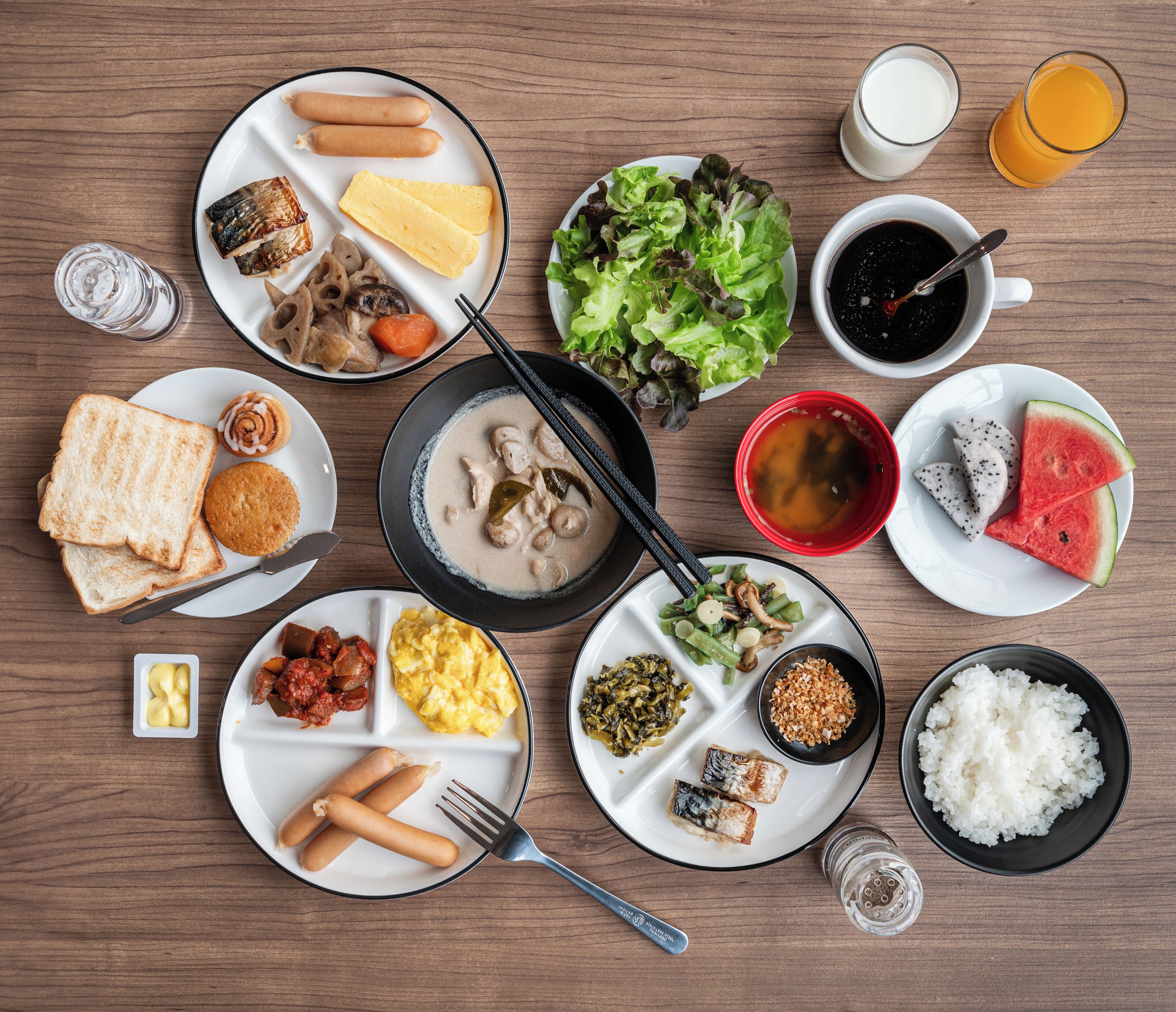A variety of dishes including fish, eggs, and rice, arranged on a wooden table.
