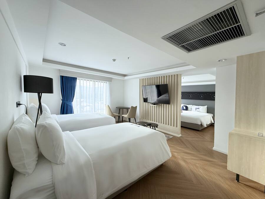 A hotel room with two beds, a TV, a desk, and a separate sleeping area.