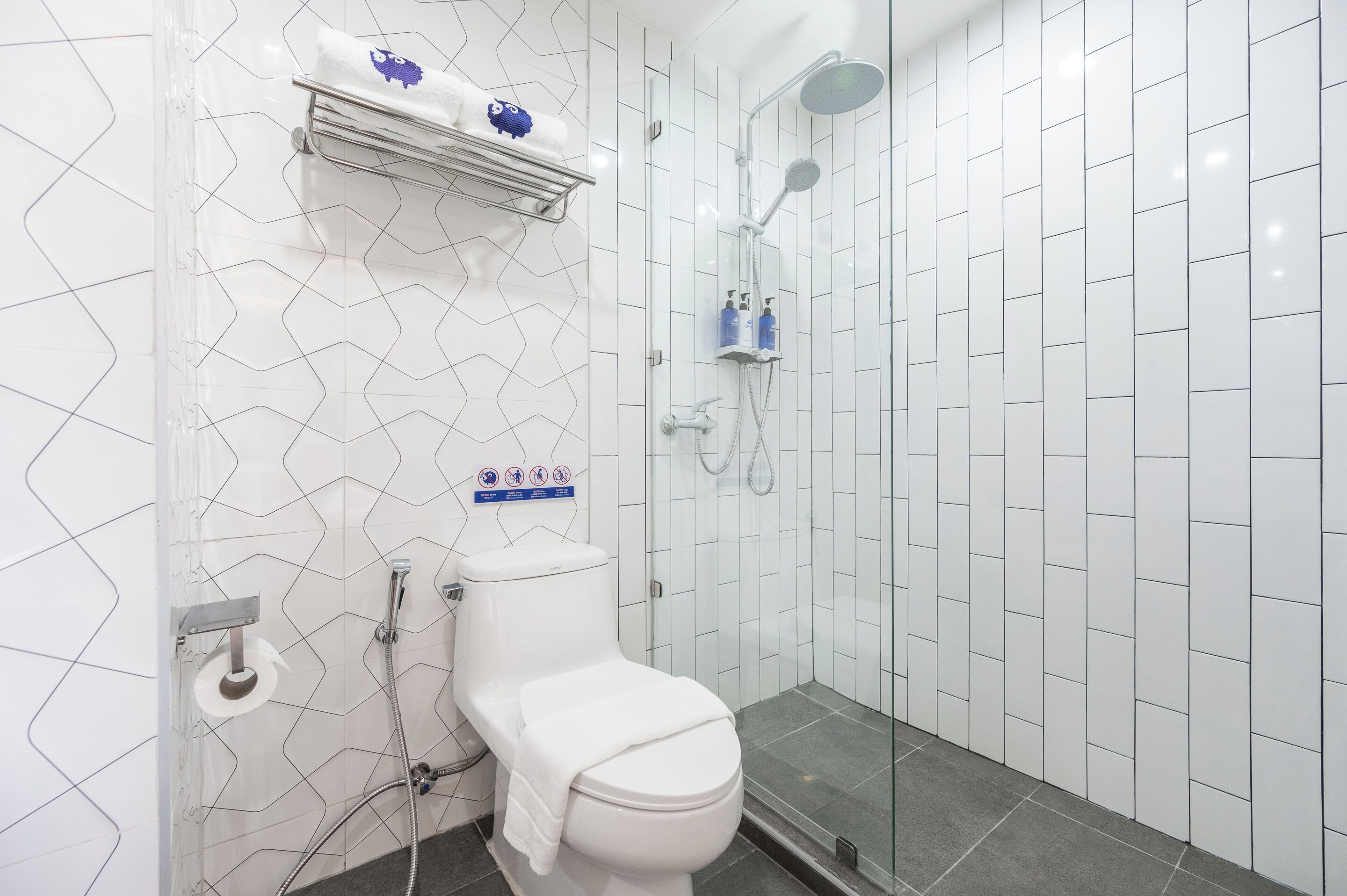 A modern bathroom with a toilet, shower, and a towel rack with toiletries.