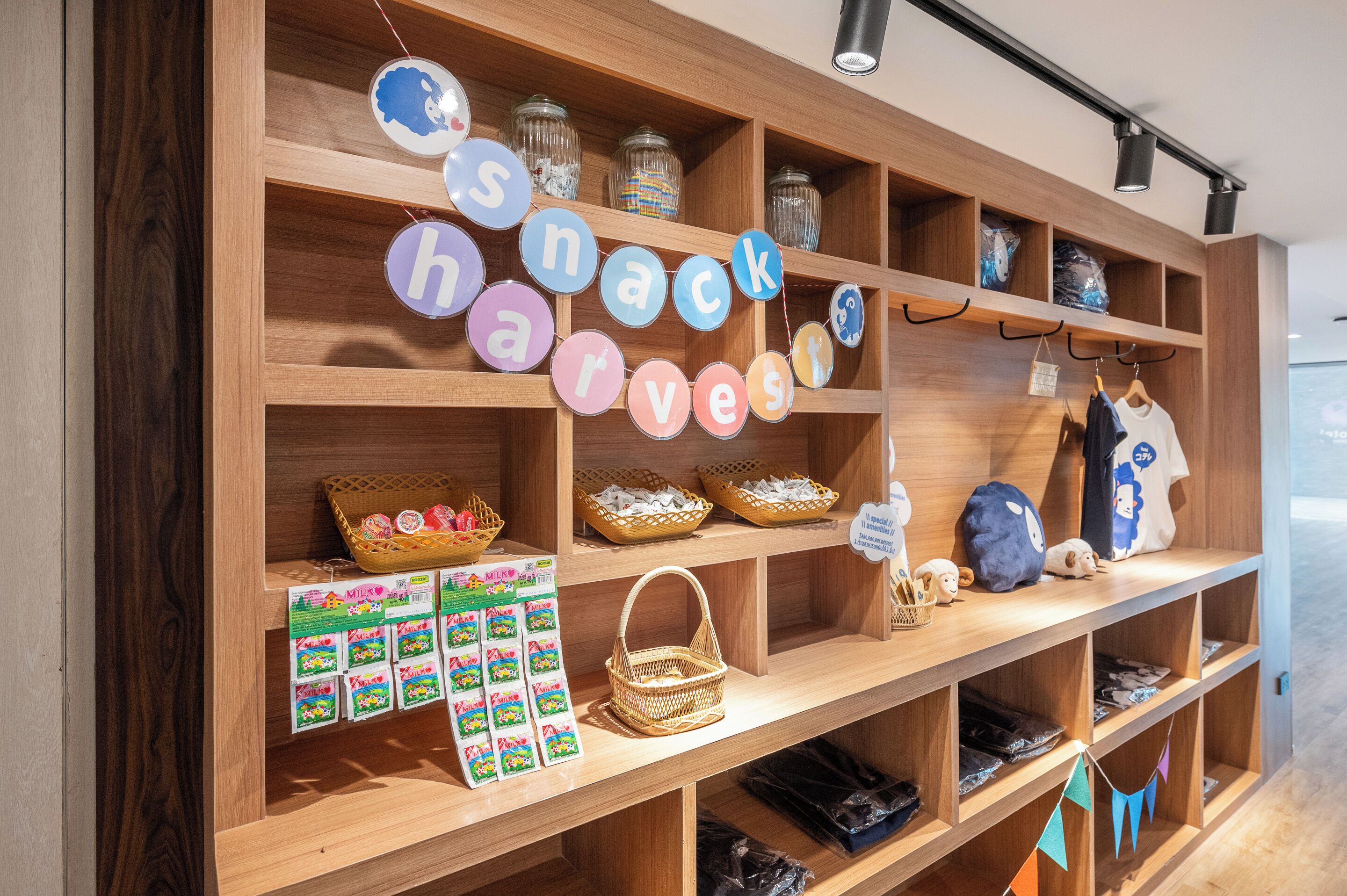 Un espositore in legno con barattoli, cesti e un cartello con scritto 'snack harvest'.