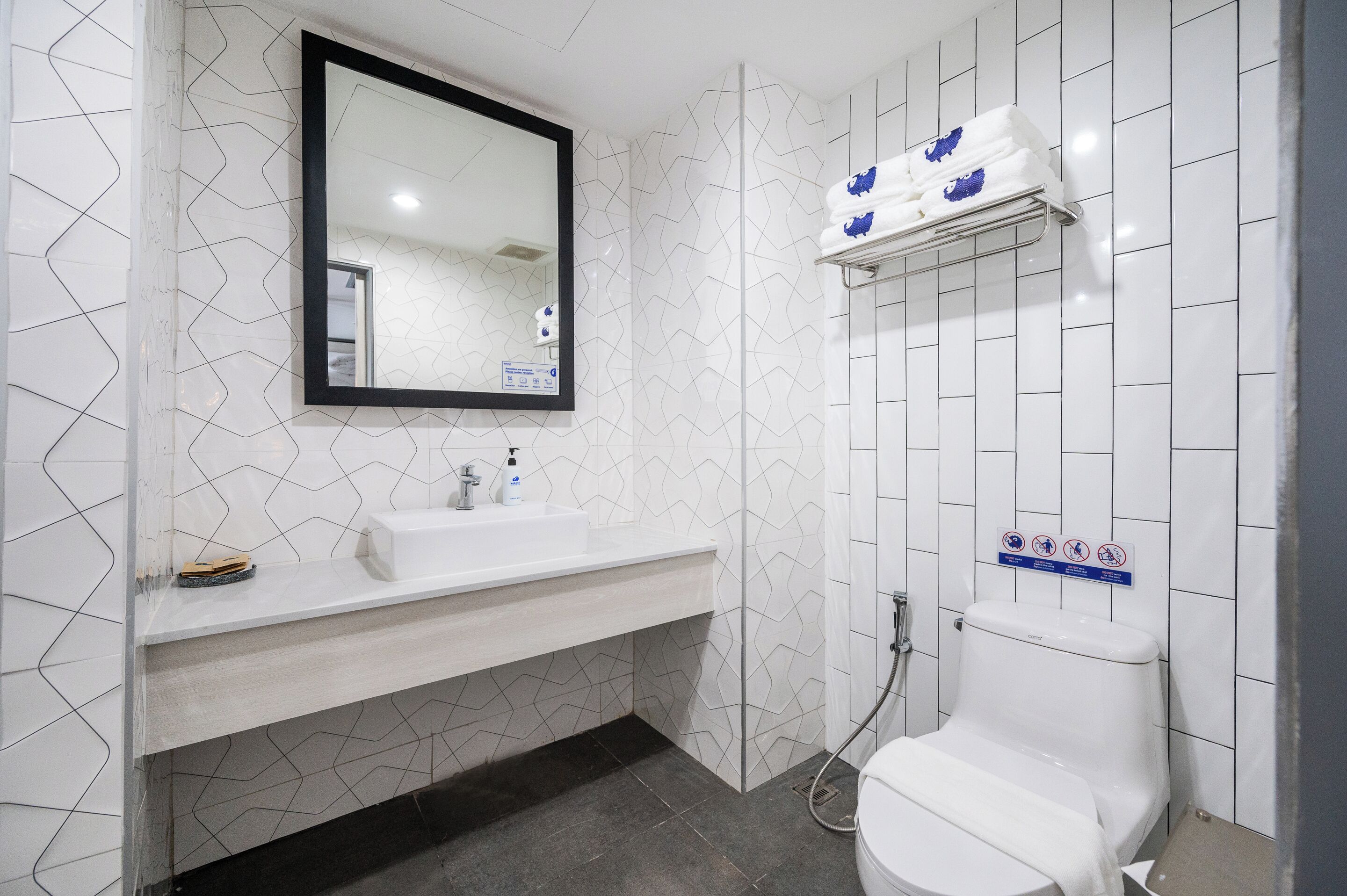 Un baño moderno con un lavamanos, espejo y retrete blancos.